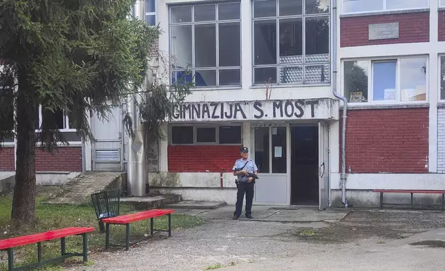 A police officer stands in front of a secondary school building in Sanski Most, northwest of Bosnia's capital, Sarajevo, Wednesday, Aug. 21, 2024, after a school employee shot and killed three people. (AP Photo/Edvin Zulic)