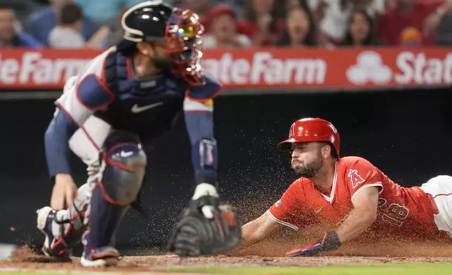 Los Angeles Angels' Nolan Schanuel, right, slides home past Atlanta Braves catcher Travis d'Arnaud, left, to score off a double by Kevin Pillar during the sixth inning of a baseball game, Saturday, Aug. 17, 2024, in Anaheim, Calif. (AP Photo/Ryan Sun)