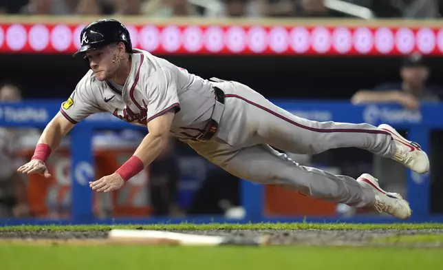 Atlanta Braves' Jarred Kelenic dives to score off a fielder's choice hit by teammate Matt Olson during the 10th inning of a baseball game against the Minnesota Twins, Tuesday, Aug. 27, 2024, in Minneapolis. (AP Photo/Abbie Parr)