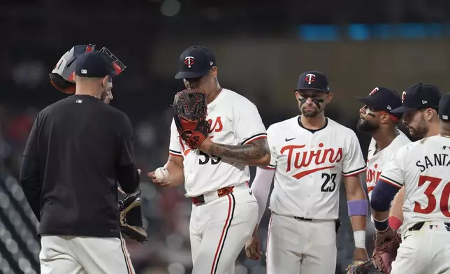 Minnesota Twins relief pitcher Jhoan Duran, center left, hands the ball to manager Rocco Baldelli for a pitching change during the 10th inning of a baseball game against the Atlanta Braves, Tuesday, Aug. 27, 2024, in Minneapolis. (AP Photo/Abbie Parr)