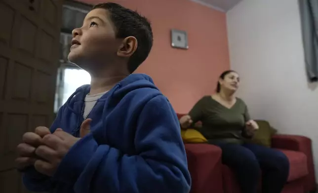 Four-year-old Murillo, who suffers from severe epilepsy, watches TV at his grandparent's home in Guaruja, Brazil, Monday, July 8, 2024. To lessen and shorten his seizures, Murillo takes a steady dose of liquid cannabidiol or CBD, that his mother, pictured in background, acquires for free through Sao Paulo state’s public health system. (AP Photo/Andre Penner)