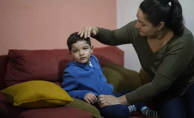 Janaina Silva caresses her four-year-old son Murillo after an epileptic seizure at her parents' home in Guaruja, Brazil, Monday, July 8, 2024. To lessen and shorten his seizures, Murillo takes a steady dose of liquid cannabidiol or CBD, that Silva acquires for free through Sao Paulo state’s public health system. (AP Photo/Andre Penner)