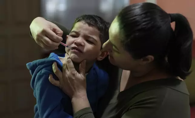 Janaina Silva gives a dose of cannabidiol or CBD, to her four-year-old son Murillo after an epileptic seizure, at her parents' home in Guaruja, Brazil, Monday, July 8, 2024. To lessen and shorten his seizures, Murillo takes a steady dose of CBD, that Silva acquires for free through Sao Paulo state’s public health system. (AP Photo/Andre Penner)