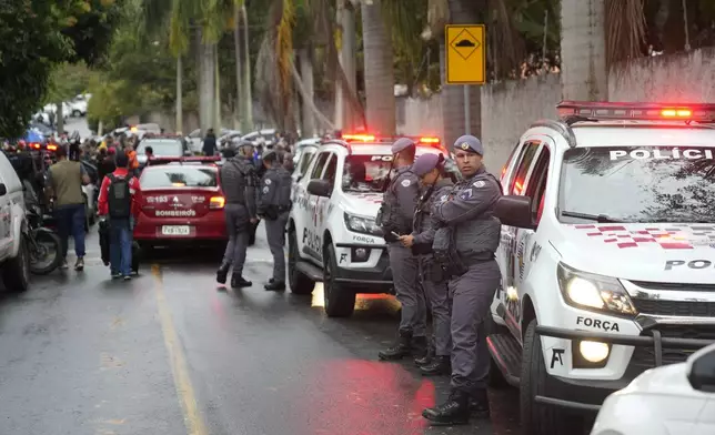 Police stand along the street leading to the gated community where a plane crashed in Vinhedo, Sao Paulo state, Brazil, Friday, Aug. 9, 2024. (AP Photo/Andre Penner)