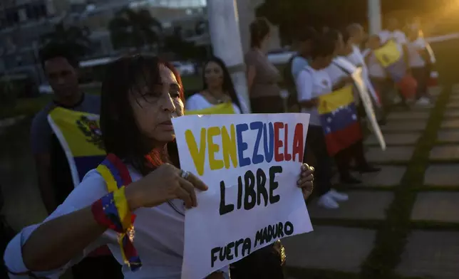 A Venezuelan national holds a sign with a message that reads in Spanish: "Free Venezuela", and "Out Maduro", during a demonstration in support of opposition Venezuelan presidential candidate Edmundo Gonzalez, in front of the Itamaraty Palace in Brasilia, Brazil, Thursday, Aug. 1, 2024. (AP Photo/Eraldo Peres)