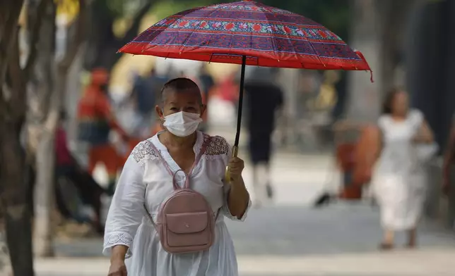 A pedestrian wears a mask due to smoke from wildfires reaching Manaus, Amazonas state, Brazil, Tuesday, Aug. 27, 2024. (AP Photo/Edmar Barros)