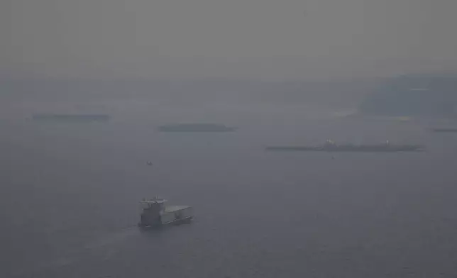 A boat navigates the Negro River amid smoke from wildfires in Manaus, Amazonas state, Brazil, Tuesday, Aug. 27, 2024. (AP Photo/Edmar Barros)