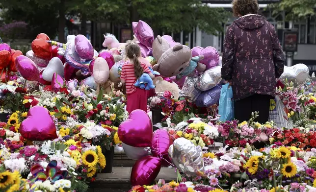 People look at the floral tribute at the Atkinson arts centre in Southport, England, Monday, Aug. 5, 2024 after three young girls were killed in a knife attack at a Taylor Swift-themed holiday club last week. Violence and unrest erupted in cities and towns across Britain, ostensibly in protest of last week's stabbing. (AP Photo/Darren Staples)