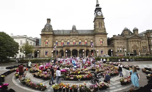 People look at the floral tribute at the Atkinson arts centre in Southport, England, Monday, Aug. 5, 2024 after three young girls were killed in a knife attack at a Taylor Swift-themed holiday club last week. Violence and unrest erupted in cities and towns across Britain, ostensibly in protest of last week's stabbing. (AP Photo/Darren Staples)