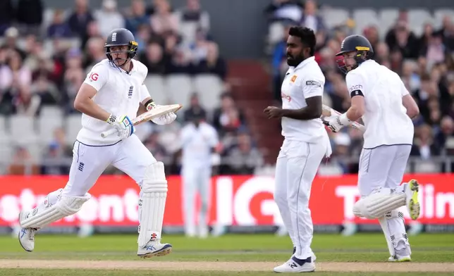 England's Jamie Smith, left, and Gus Atkinson in action as Sri Lanka's Asitha Fernando, centre, watches on during day three of the First Test match between England and Sri Lanka at Emirates Old Trafford, Manchester, England, Thursday Aug. 22, 2024. (Nick Potts/PA via AP)