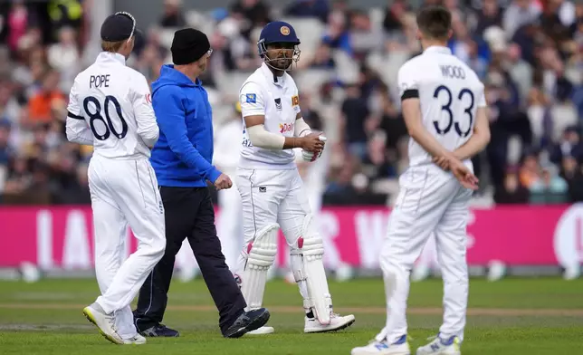 Sri Lanka's Dinesh Chandimal, center, leaves the field after picking up an injury on day three of the First Test match between England and Sri Lanka at Emirates Old Trafford, Manchester, England, Friday Aug. 23, 2024. (Nick Potts/PA via AP)