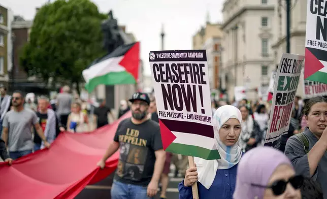 Demonstrators wave flags and hold placards as they take part in a march in support of Palestinians, in London, Saturday, Aug. 3, 2024. (AP Photo/Alberto Pezzali)