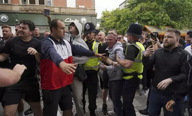 Police officers face protesters during a protest in Nottingham, England's Market Square on Saturday, Aug. 3, 2024, following Monday's stabbing attacks in Southport, in which three young children were killed. (Jacob King/PA via AP)