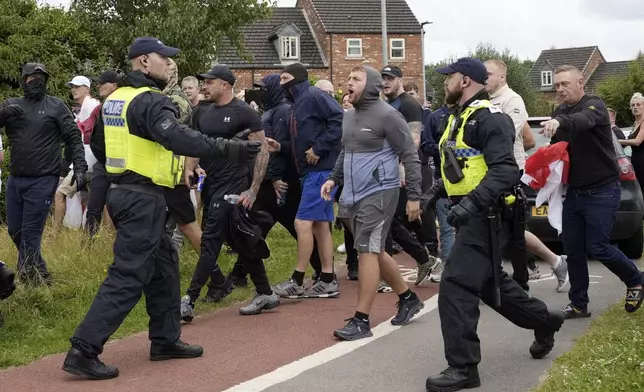 Police officers face protesters outside the Holiday Inn Express in Rotherham, England, Sunday, Aug. 4, 2024. The violence erupted earlier this week in cities and towns across Britain, ostensibly in protest of Monday's mass stabbing in Southport. A 17-year-old male has been arrested and charged with murder and attempted murder in connection with the Southport attack. False rumors spread online that the young man was a Muslim and an immigrant, fueling anger among far-right supporters. (Danny Lawson/PA via AP)