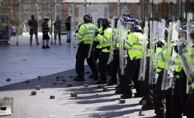 Rubble lies at the feet of police officers thrown by protesters in Liverpool, England, Saturday Aug. 3, 2024, following the stabbing attacks on Monday in Southport, in which three young children were killed. (James Speakman/PA via AP)