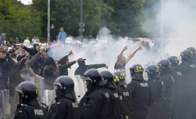 Police officers face protesters during an anti-immigration demonstration outside the Holiday Inn Express in Rotherham, England, Sunday Aug. 4, 2024. (Danny Lawson/PA via AP)