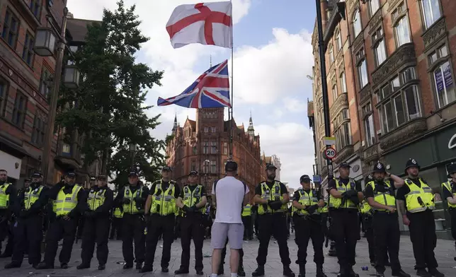 Police officers face a lone protester carrying English and British flags during a protest in Nottingham, England's Market Square Saturday Aug. 3, 2024, following the stabbing attacks on Monday in Southport, in which three young children were killed. (Jacob King/PA via AP)