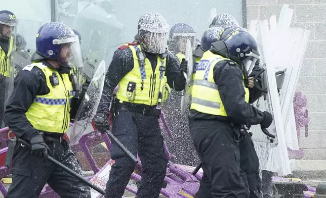 Fire extinguishers are used on police officers as trouble flares during an anti-immigration protest outside the Holiday Inn Express in Rotherham, England, Sunday Aug. 4, 2024. (Danny Lawson/PA via AP)