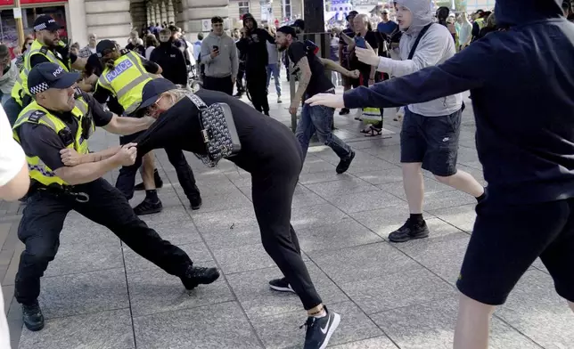 A police officer holds onto a woman during a protest in Nottingham, England's Market Square Saturday Aug. 3, 2024, following the stabbing attacks on Monday in Southport, in which three young children were killed. (Jacob King/PA via AP)