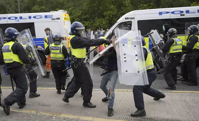 Police officers with protesters as trouble flares during an anti-immigration protest outside the Holiday Inn Express in Rotherham, England, Sunday Aug. 4, 2024. (Danny Lawson/PA via AP)