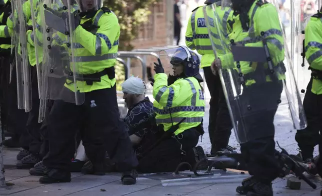 Police and medics attend to a person during a protest in Liverpool, England, Saturday Aug. 3, 2024, following the stabbing attacks on Monday in Southport, in which three young children were killed. (James Speakman/PA via AP)