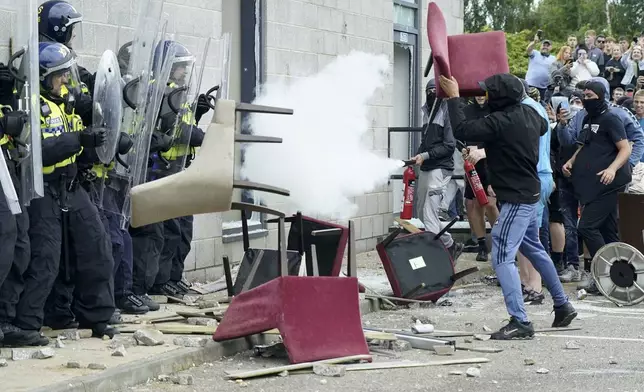 A chair is thrown at police officers as trouble flares during an anti-immigration protest outside the Holiday Inn Express in Rotherham, England, Sunday Aug. 4, 2024. (Danny Lawson/PA via AP)