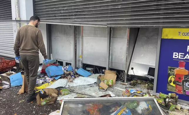 A man tries to clean up a supermarket damaged by fire on Donegall Road following anti-immigration protests in Belfast, Northern Ireland, Sunday, Aug. 4, 2024. The violence erupted earlier this week in cities and towns across Britain, ostensibly in protest of Monday's mass stabbing in Southport. A 17-year-old male has been arrested and charged with murder and attempted murder in connection with the Southport attack. False rumors spread online that the young man was a Muslim and an immigrant, fueling anger among far-right supporters. (Jonathan McCambridge/PA via AP)