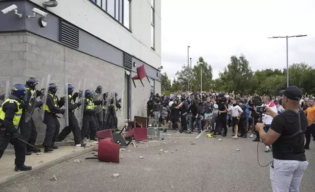 A chair is thrown at police officers as trouble flares during an anti-immigration protest outside the Holiday Inn Express in Rotherham, England, Sunday Aug. 4, 2024. (Danny Lawson/PA via AP)