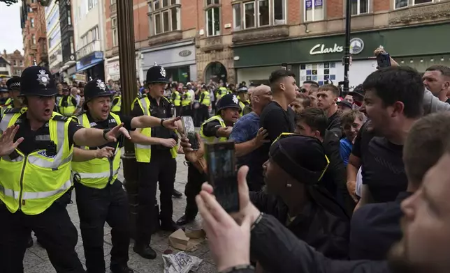 Police officers face protesters during a protest in Nottingham, England's Market Square on Saturday, Aug. 3, 2024, following Monday's stabbing attacks in Southport, in which three young children were killed. (Jacob King/PA via AP)