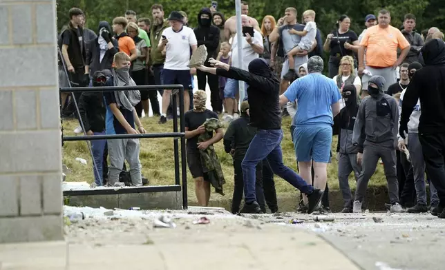 Objects are thrown as trouble flares during an anti-immigration protest outside the Holiday Inn Express in Rotherham, England, Sunday Aug. 4, 2024. (Danny Lawson/PA via AP)