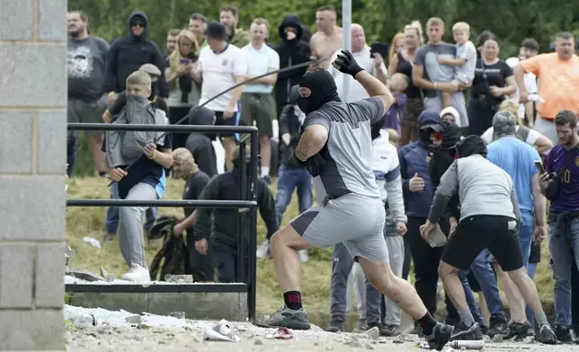 Objects are thrown as trouble flares during an anti-immigration protest outside the Holiday Inn Express in Rotherham, England, Sunday Aug. 4, 2024. (Danny Lawson/PA via AP)