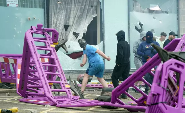 Demonstrators smash windows as trouble flares during an anti-immigration protest outside the Holiday Inn Express in Rotherham, England, Sunday Aug. 4, 2024. (Danny Lawson/PA via AP)