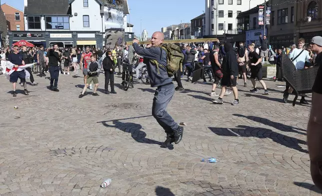 A man swings a length of wood as people protest in Blackpool, England, Saturday Aug. 3, 2024, following the stabbing attacks on Monday in Southport, in which three young children were killed. (Michael Holmes/PA via AP)