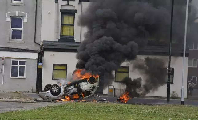 A car burns after being overturned during an anti-immigration protest in Middlesbrough, England, Sunday Aug. 4, 2024. (Owen Humphreys/PA via AP)