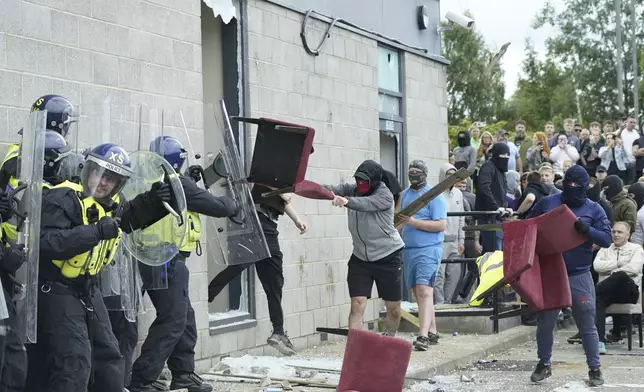 A chair is thrown at police officers as trouble flares during an anti-immigration protest outside the Holiday Inn Express in Rotherham, England, Sunday Aug. 4, 2024. (Danny Lawson/PA via AP)