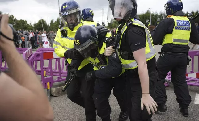 A police officer is injured as trouble flares during an anti-immigration protest outside the Holiday Inn Express in Rotherham, England, Sunday Aug. 4, 2024. (Danny Lawson/PA via AP)