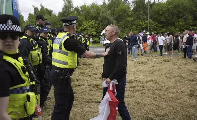 Police officers face protesters outside the Holiday Inn Express in Rotherham, England, Sunday, Aug. 4, 2024. The violence erupted earlier this week in cities and towns across Britain, ostensibly in protest of Monday's mass stabbing in Southport. A 17-year-old male has been arrested and charged with murder and attempted murder in connection with the Southport attack. False rumors spread online that the young man was a Muslim and an immigrant, fueling anger among far-right supporters. (Danny Lawson/PA via AP)