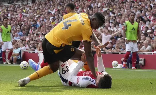 Arsenal's Kai Havertz, bottom, challenges for the ball with Wolverhampton Wanderers' Yerson Mosquera during the English Premier League soccer match between Arsenal and Wolverhampton Wanderers at Emirates Stadium in London, England, Saturday, Aug. 17, 2024. (AP Photo/Frank Augstein)