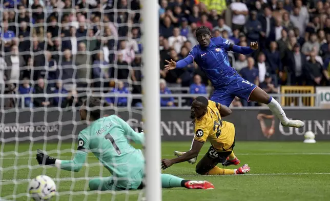 Chelsea's Noni Madueke, top, scores during the English Premier League soccer match between Wolverhampton Wanderers and Chelsea at Molineux Stadium, Wolverhampton, England. Sunday Aug. 25, 2024. (Joe Giddens/PA via AP)