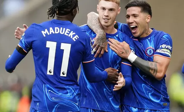 Chelsea's Cole Palmer, center, celebrates scoring with teammates Noni Madueke, left, and Enzo Fernandez during the English Premier League soccer match between Wolverhampton Wanderers and Chelsea at Molineux Stadium, Wolverhampton, England. Sunday Aug. 25, 2024. (Nick Potts/PA via AP)