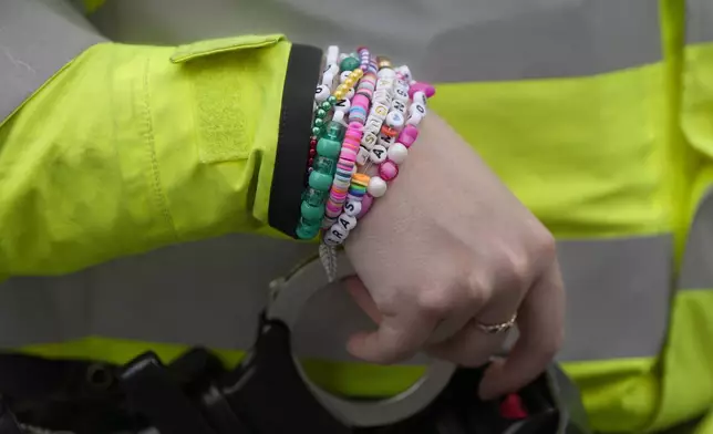 A police officer wears wrist bands that have names of Swift songs as fans of singer Taylor Swift, called Swifties, arrive at Wembley Stadium in London, Thursday, Aug. 15, 2024 for the first of five concerts of Taylor Swift's Eras Tour.(AP Photo/Alastair Grant)