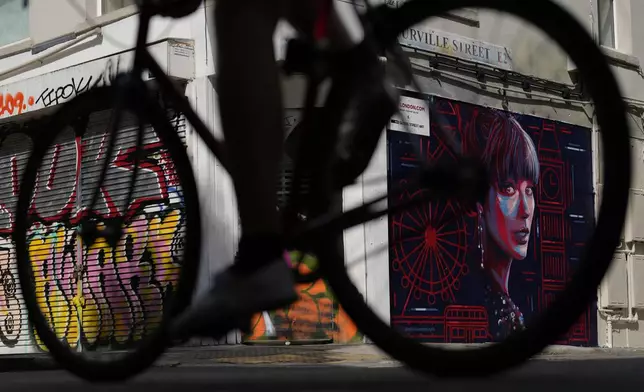 A cyclist passes by new mural portrait of Taylor Swift designed by Kate Clayton as it is unveiled in Shoreditch in east London, Tuesday, Aug. 13, 2024. (AP Photo/Alastair Grant)