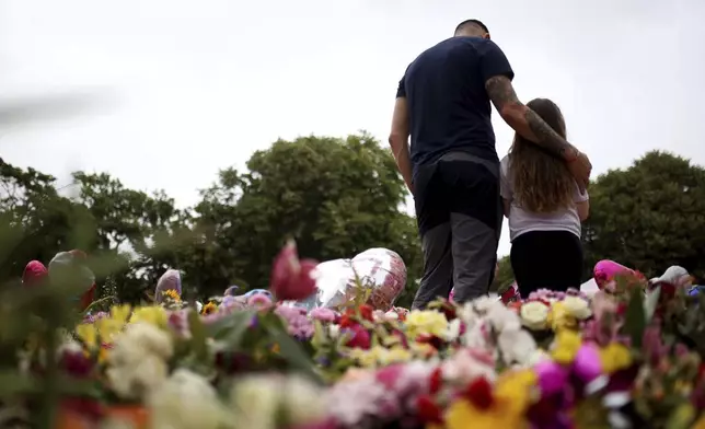 Members of the public place and look at the tributes outside the Town Hall in Southport, England, Monday Aug. 5, 2024, ahead of a vigil to remember the victims of the stabbing attack last Monday. (Ryan Jenkinson/PA via AP)