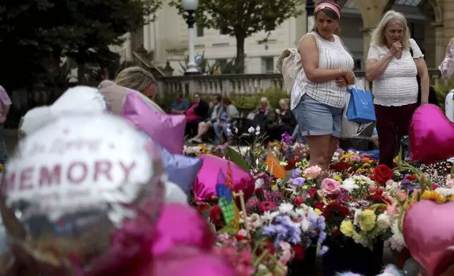 Members of the public place and look at the tributes outside the Town Hall in Southport, England, Monday Aug. 5, 2024, ahead of a vigil to remember the victims of the stabbing attack last Monday. (Ryan Jenkinson/PA via AP)