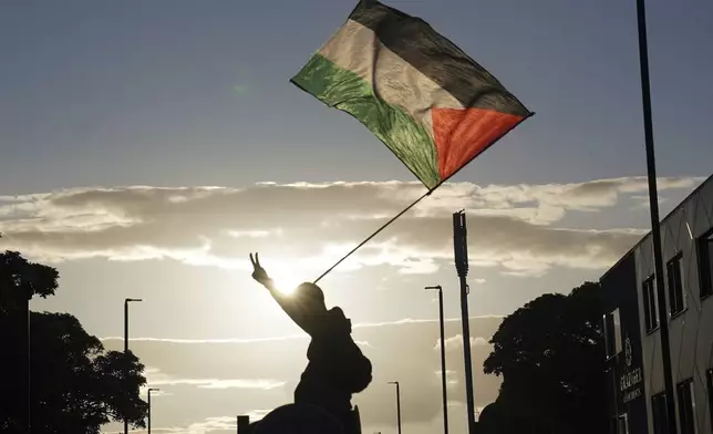 An anti-racism protesters waves a Palestinian flag in Newcastle, England, Wednesday Aug. 7, 2024, as anti-immigration groups plan to demonstrate at dozens of locations throughout the country following a week of rioting fueled by misinformation over a stabbing attack against young girls. (PA via AP)