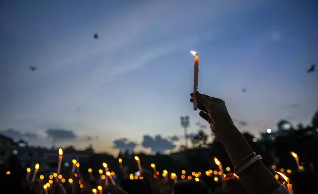 CORRECTS TO CHANGE THE TERM MURDER TO KILLING - Women hold candles as they stage a protest against the rape and killing of a trainee doctor at a government hospital last week, in Guwahati, India, Friday, Aug. 16, 2024. (AP Photo/Anupam Nath)