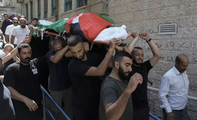 CORRECTS DATE - Mourners carry the body of Khalil Ziada, wrapped with a Palestinian flag, who died during an Israeli settler attack in the Wadi Rahal village, as they leave at a hospital morgue during his funeral in the West Bank city of Bethlehem, Tuesday, Aug. 27, 2024. (AP Photo/Mahmoud Illean)