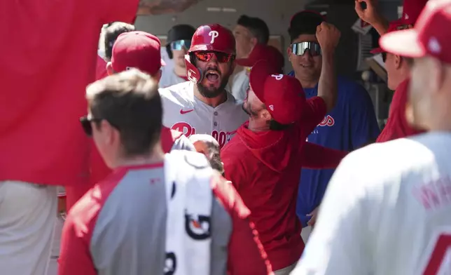 CORRECTS TO KYLE SCHWARBER NOT JEFF HOFFMAN - Philadelphia Phillies' Kyle Schwarber celebrates with teammates in the dugout after hitting a home run off Seattle Mariners pitcher Logan Gilbert during the first inning of a baseball game, Sunday, Aug. 4, 2024, in Seattle. (AP Photo/Liv Lyons)