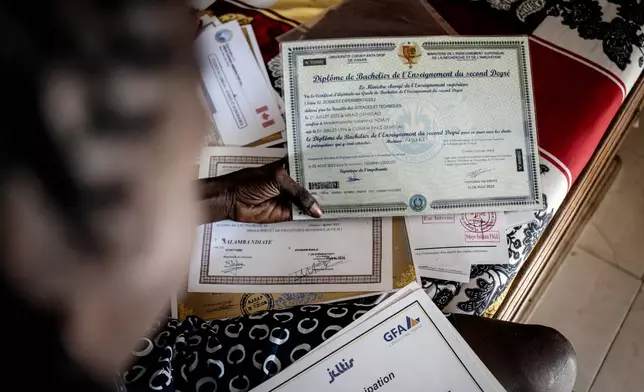 CORRECTS FAMILY NAME TO NDIAYE - Salamba Ndiaye, a 28-year-old who tried to migrate to Europe twice, checks her school certificates at her house in Thiaroye-Sur-Mer, Senegal, Friday, Aug. 23, 2024. Ndiaye is one of thousands of young Senegalese who try to flee poverty and the lack of job opportunities in the West African country each year to head to Spain. More than 22,300 people have landed on the Canary Islands from January to mid-August this year, (AP Photo/Annika Hammerschlag)