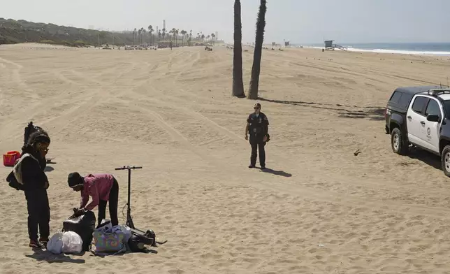 A couple packs their personal belonging as Los Angeles Police and Los Angeles County Department of Beaches and Harbors workers removed their tent as they conduct a cleanup operation to remove homeless encampments at Dockweiler State Beach in Playa del Rey, Los Angeles, on Thursday, Aug. 22, 2024. (AP Photo/Damian Dovarganes)